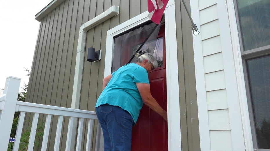 an older woman prepares to unlock the front door to her home