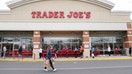 FILE: A shopper wearing a protective face mask passes near a self-distancing queue outside Trader Joe&apos;s